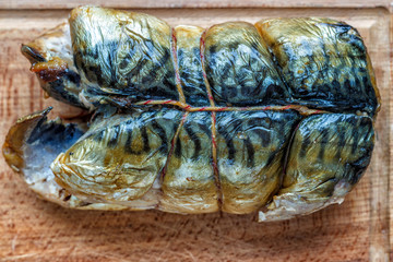 Smoked fish mackerel on a wooden background, close-up, top view.