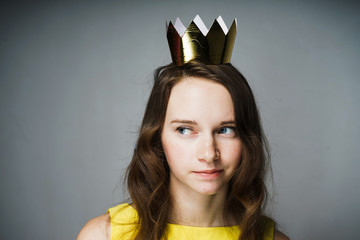 cute young woman in a yellow dress, wearing a gold crown, waiting for Mother's Day