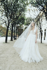 Fototapeta na wymiar Mysterious and happy bride whirls between the trees somewhere in Paris