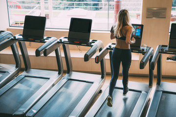 woman running on treadmills in a gym with beautiful light from the window gym machines