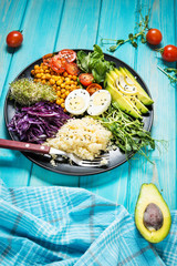 Healthy vegan lunch bowl. Vegan buddha bowl. Vegetables and nuts in buddha bowl on blue wood background.