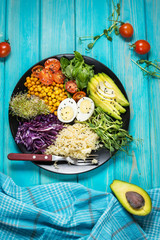 Healthy vegan lunch bowl. Vegan buddha bowl. Vegetables and nuts in buddha bowl on blue wood background. Top