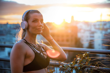 sportswoman outdoors in the gym resting enjoying the views listening music