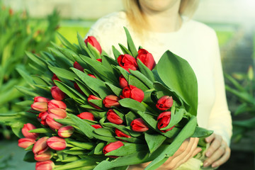 Bouquet of tulips in the hands of the girl.Bouquet of red tulips. Spring gift for a girl .