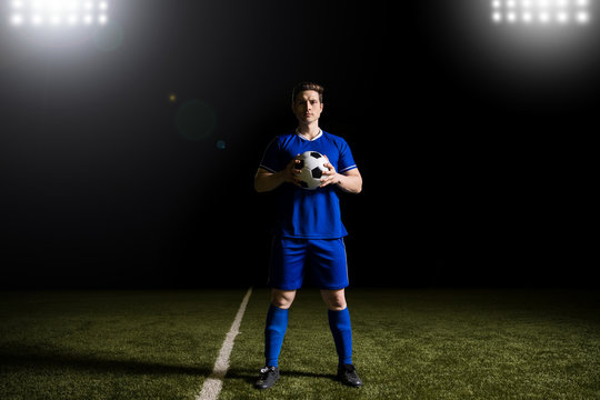 Male football player in blue uniform on soccer field