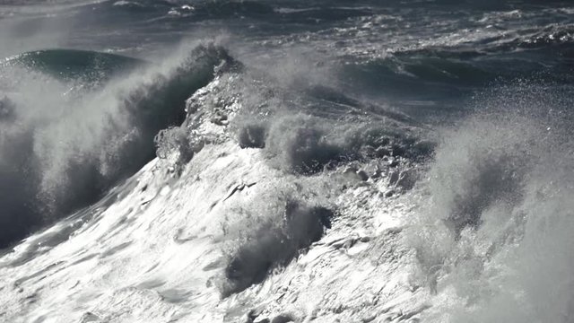 Ocean wave crushing lava coast. Slow motion shot.
