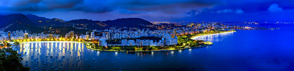 Panoramic image of Rio de Janeiro seen from above at night with its lights, hills, streets, Gaunabara bay and Santos Dumont airport