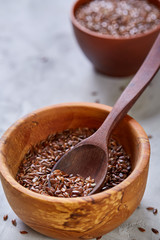 Flax seeds in wooden bowl and spoon on rustic wooden background, top view, shallow depth of field