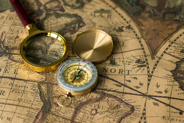 Retro compass with old map and magnifier