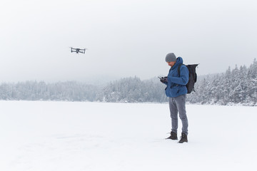 Young man flying a drone in winter