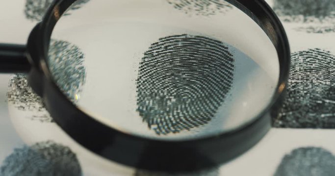 Macro shooting of the investigation of the fingerprints with a magnifying glass. Close up