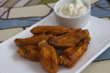 Hot chicken wings with blue cheese dipping sauce in casual presentation