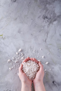 Sea Salt Crystals In Women Hand On White Background, Overhead, Close-up, Vertical.