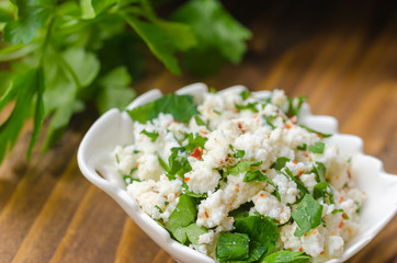 homemade curd cheese with parsley, and red pepper on a wooden table