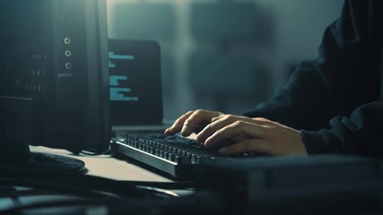 Computer hacker in server room with multiple LCD panels, laptop and scrolling code. - Powered by Adobe