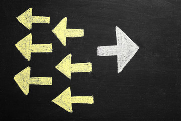 Fototapeta premium Chalk drawings of arrows and one standing out on blackboard. Difference and uniqueness concept