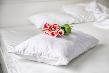 Obraz na płótnie Canvas Soft pillow with tulips on bed