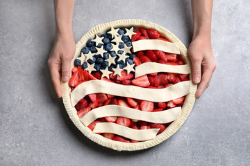 Woman with American flag pie on grey background