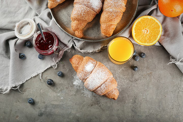 Tasty croissant and glass of juice on table