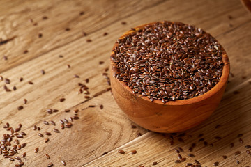 Wooden spoon with flax seeds on rustic background, top view, close-up, shallow depth of field, selective focus