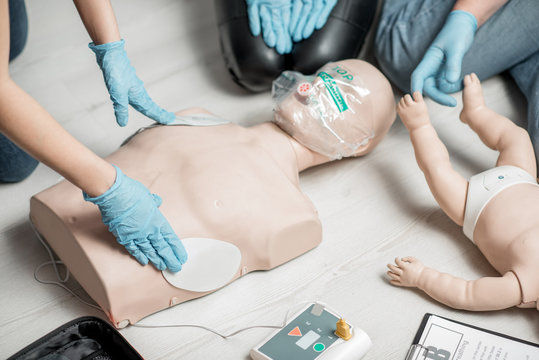 Clinging a contacts on a dummy teaching how to make defibrillation during the first aid training