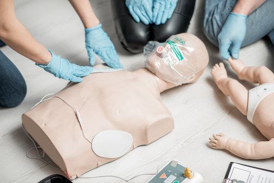 Clinging a contacts on a dummy teaching how to make defibrillation during the first aid training