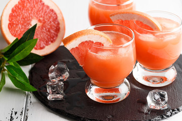 Grapefruit juice and ripe grapefruits on a wooden background