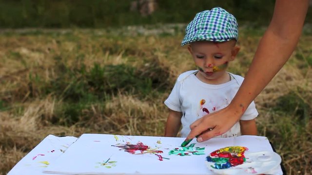 Funny little artist learn to paint a picture in nature, parent hand reveal art