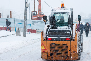 Yellow snowplow removing snow during heavy snowfall. Winter street maintenance in hard weather conditions