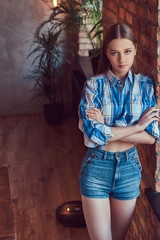 A young slim sexy girl in a jeans jacket and flannel shirt leani