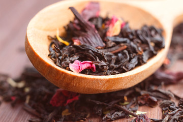 Composition of natural tea with a leaves of rose. Macro photo of tea petals on a wooden spoon with...
