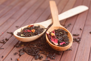 Composition of natural tea with a leaves of rose. Macro photo of tea petals on a wooden spoon with a rose. Tea with the ingredients of flowers and rose tea located on a wooden Board.