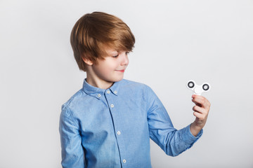 Young boy holding popular fidget spinner toy - close up portrait. Happy smiling child playing with...