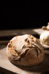 Freshly baked bread on wooden table on dark background