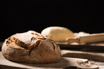 Freshly baked bread on wooden table on dark background