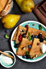 Homemade pancakes with berries and cream sauce on a black background.