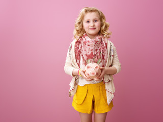 happy modern girl on pink background with piggy bank