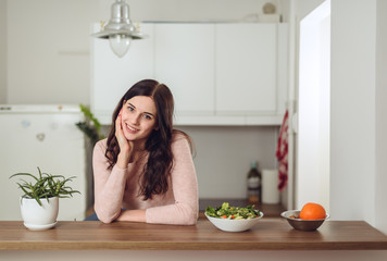 Smiling young woman in the kitchen near desk