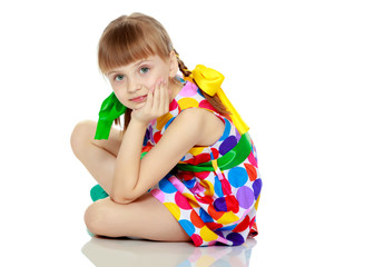 A little girl in a dress with a pattern from multi-colored circl