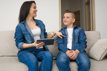 Happy family sitting on sofa and using digital tablet at home