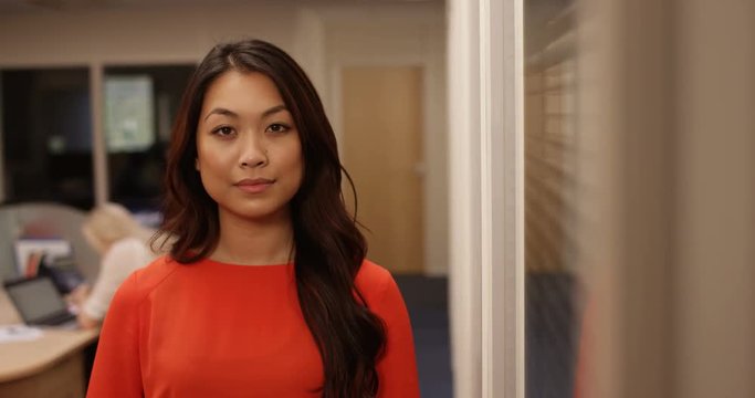 4K Portrait serious ambitious businesswoman in the office with coworkers in background. Slow motion.