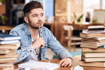 Freelancer man taking noteson paper sitting at desk.
