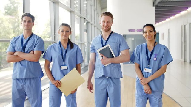 Medical Interns Wearing Scrubs Walk Towards Camera in Busy Hospital