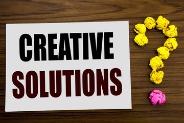 Fototapeta premium Hand writing text caption inspiration showing Creative Solutions. Business concept for Brainstorm Thinking written on white note paper on the wooden background with question mark on the end.