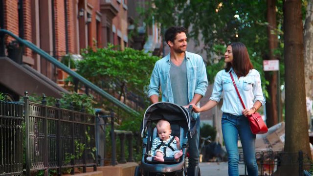 Couple walking in street with baby in a stroller, close up