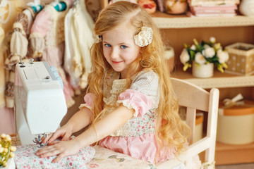 a small blonde girl with long hair smiling beautiful baby girl 6 years in a retro dress sew on a...