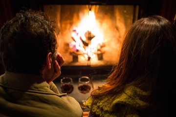Couple sitting at warm fireplace with wine