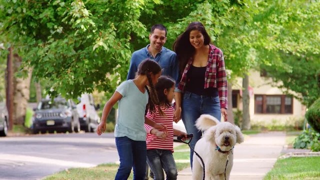Family Walking Dog Along Suburban Street