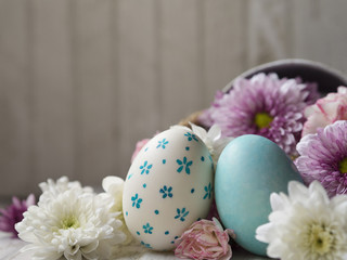 Obraz na płótnie Canvas Hand painting Easter eggs with white color egg shell and blue little flower pattern painting, and blue marble pattern painting Easter eggs and Spring flower in vintage pot with white wooden background