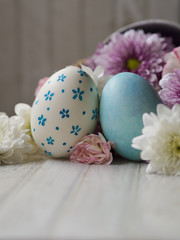 Obraz na płótnie Canvas Hand painting Easter eggs with white color egg shell and blue little flower pattern painting, and blue marble pattern painting Easter eggs and Spring flower in vintage pot with white wooden table